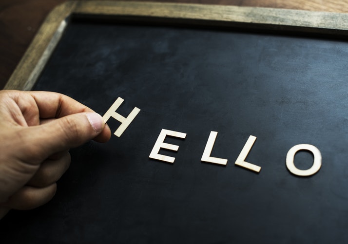 hello in white letters being added to a blackboard