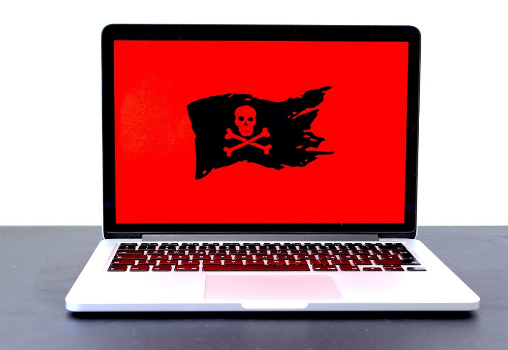 malware infected laptop with black pirate flag on red background